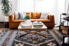an eclectic living area with a folksy rug, a floor lamp, a rust-colored sofa and baskets for storage