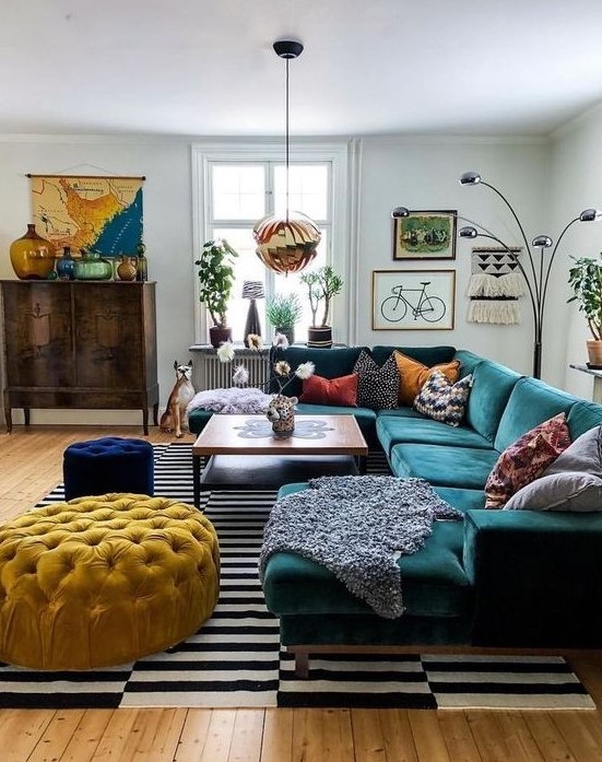 An eclectic living space with jewel tone furniture, a striped rug, a gallery wall and a vintage cabinet.