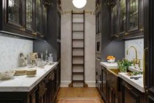 an elegant dark kitchen with traditional dark cabinets, a ladder to get things from upper cabinets and neutral stone countertops