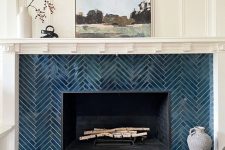 an elegant fireplace clad with navy herringbone tiles, with a mantel and some decor is a lovely idea for a modern space