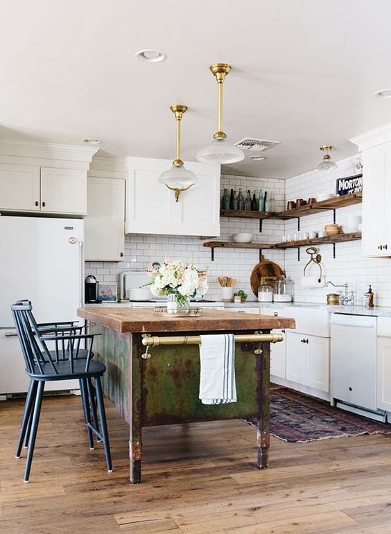 white cabinets paired with a shabby chic wooden kitchen island and vintage blue stools plus refined pendant lamps