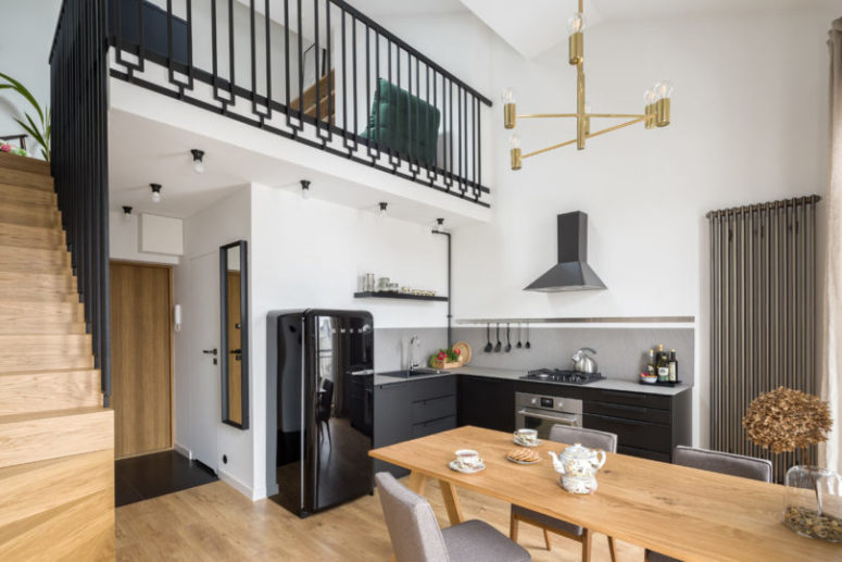 The kitchen is done in black and grpahite grey, with white countertops and a black Smeg fridge