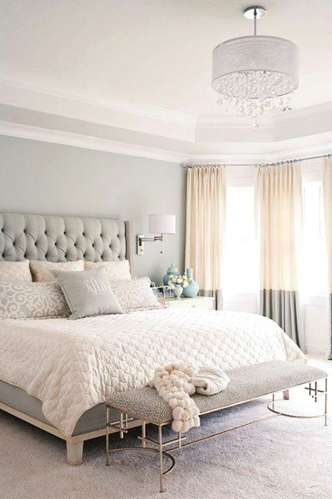 a soothing bedroom in light greys, with an upholstered bed, two tone curtains and an elegant bench