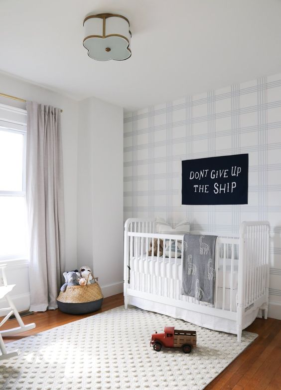 a welcoming and light-filled nursery with a light shaded plaid statement wall and a fun white polka dot rug