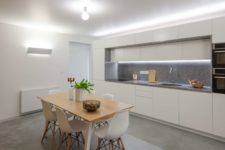 03 The kitchen is minimal, with a stylish dining set, sleek white cabinets and built-in lights