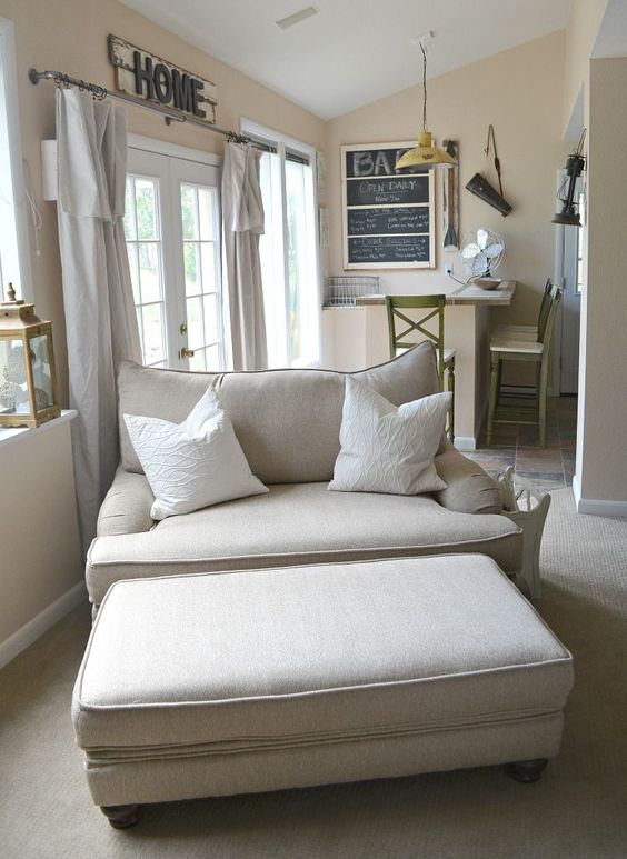a cozy neutral loveseat and a matching ottoman perfectly fit a modern farmhouse living room