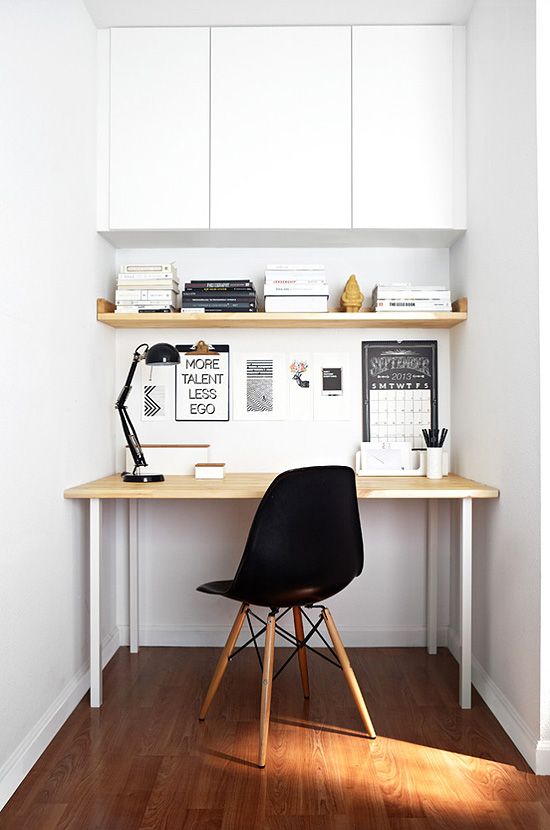 a mini home office nook in white, with a closed storage space and a sleek desk plus a black lamp and chair