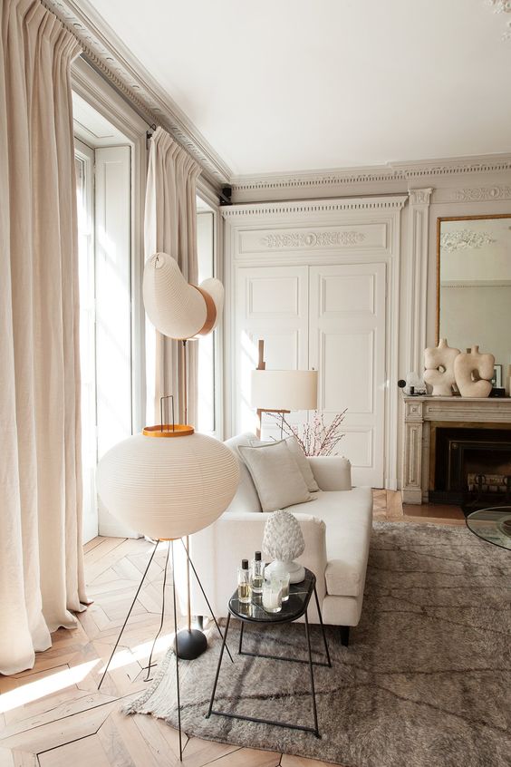 an elegant neutral Parisian living room with off-whites, greys and some beige touches is filled with light