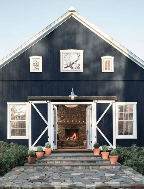 a navy and white barndominium with sliding doors and white framed windows looks very welcoming