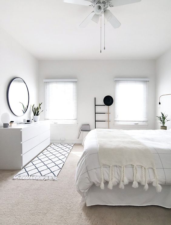 a pure white bedroom with a Nordic feel, a whiet sleek sideboard and shades on the windows