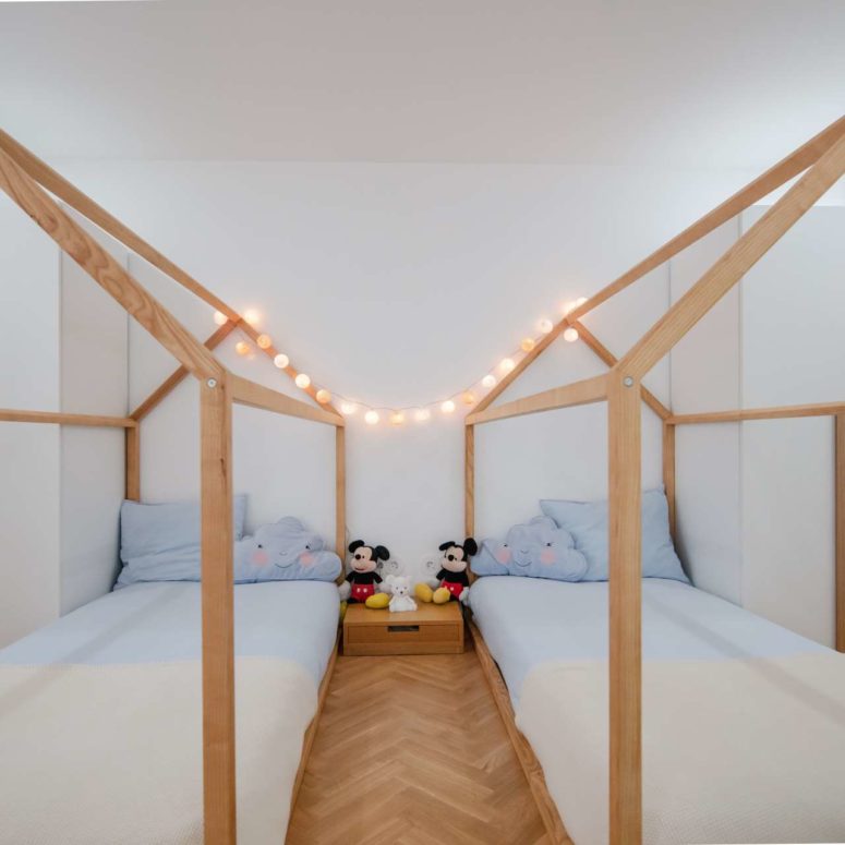 The kids' room is done with two house-shaped beds, lights and touches of blue