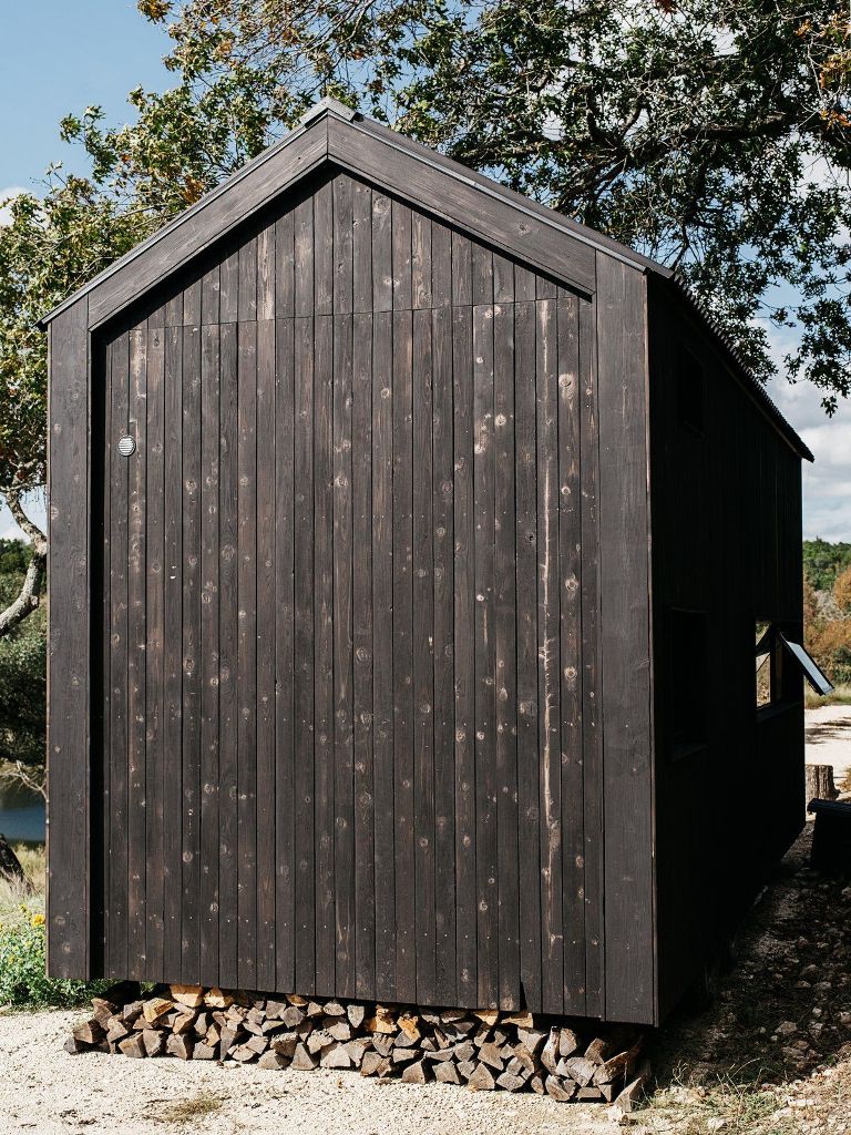 The cabin seems to be floating a few inches above the ground, allowing space for a wood storage niche underneath