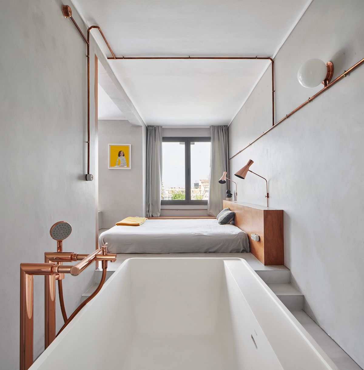 The bathroom is placed next to the bedroom, with a bathtub and elegant hardware