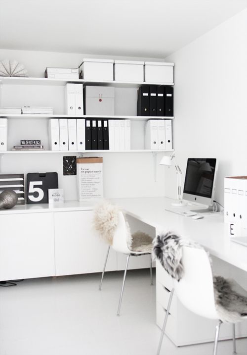 a contemporary white home office with open shelving, cabinets and a white shared desk for working