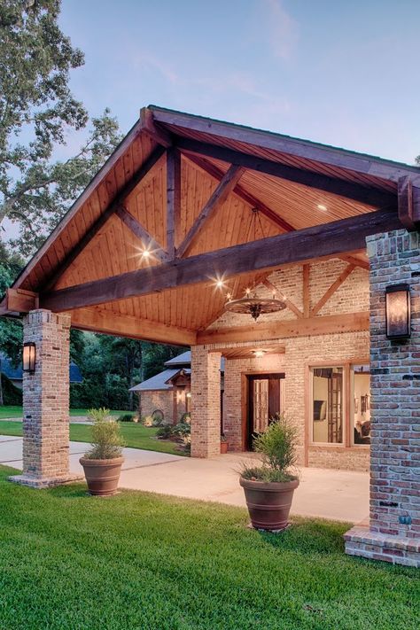 a stylish barndominium with brick pillars and a classic gabled roof with beams that feels very cozy and rustic