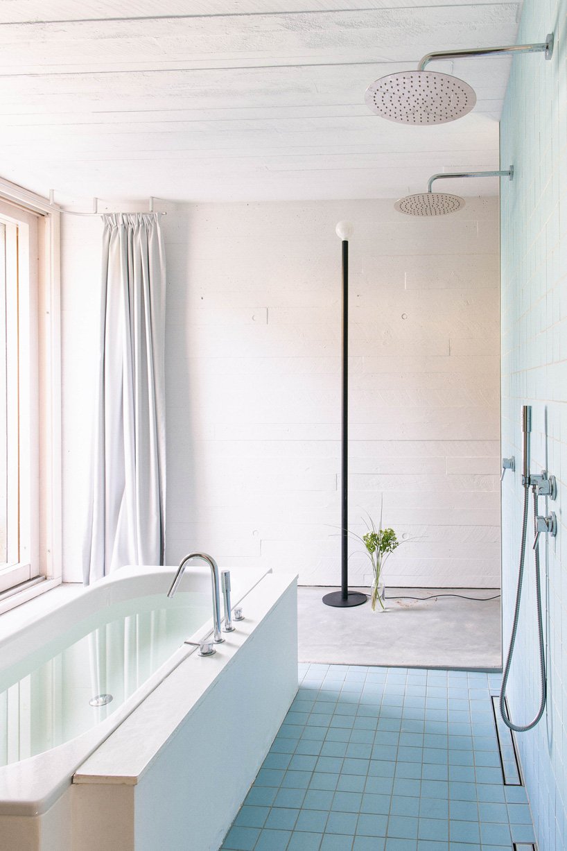The bathroom is done with white and neutral tiles and concrete, and there's a bathtub