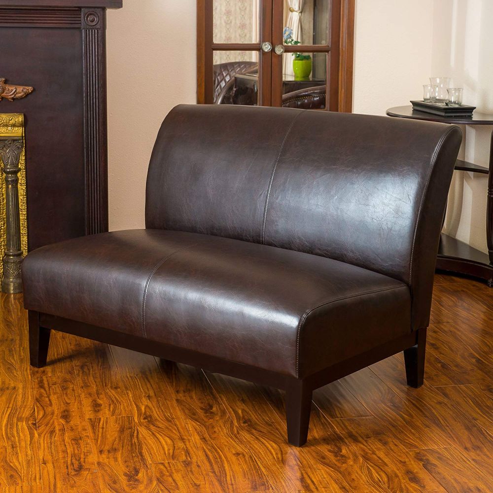 A loveseat of brown leather, with stained wooden legs will make an accent not only with its look but also with a texture