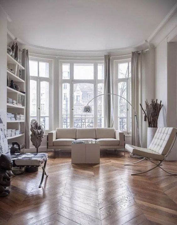 A contemporary Parisian living room with all whites and a hardwood parquet floor to soften the space
