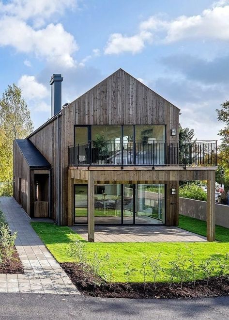 a contemporary yet rustic barndominium with glazed walls and a terrace on the upper floor
