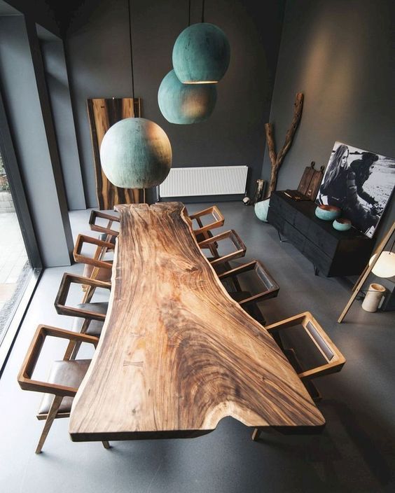 a super eye-catchy dining table made of a live edge slab and catchy geometric chairs plus teal pendant lamps over the table