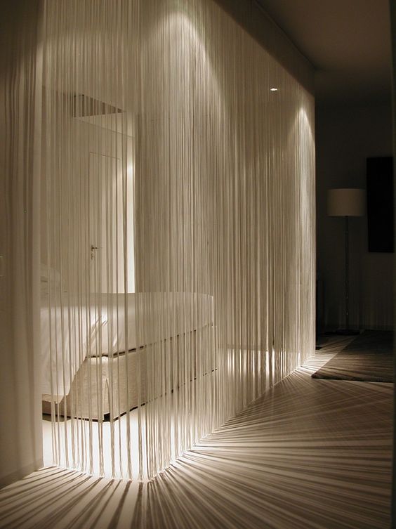 a white fringe curtain is a cool take on a usual white sheer curtain, it divides spaces and doesn't look obtrusive