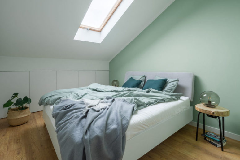 The bedroom is soothing, with a skylight, an upholstered bed and a larrge storage unit hidden behind sleke panels