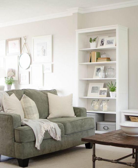a muted green loveseat with neutral pillows matches the modern famrhouse decor of the living room