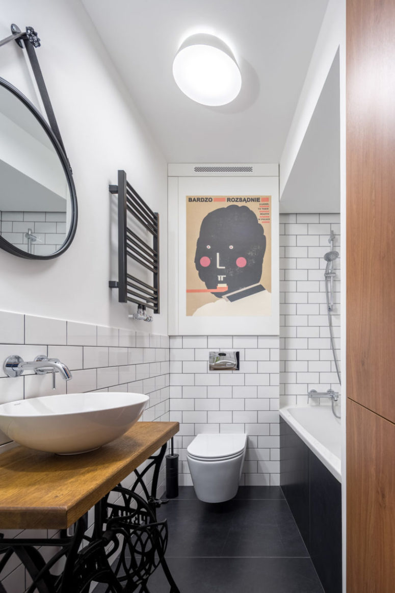 The bathroom is done in black and white, with an artwork, a unique vanity of a Zinger sewing machine and subway tiles