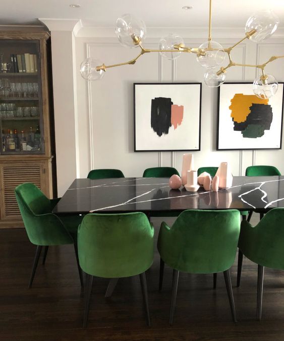 a dining table of black stone and emerald chairs to contrast and highlight the dark tabletop a lot