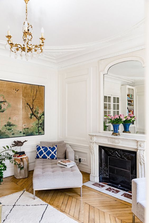 White walls with molding and warm colored hardwood parquet floors create a chic combo for a Parisian living room