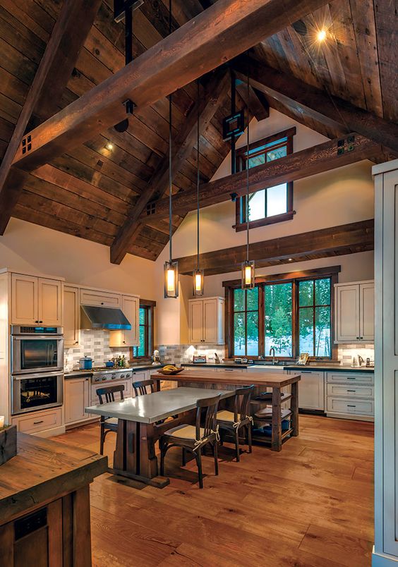 a barndominium kitchen and dining space with a ceiling with wooden beams and suspended lamps