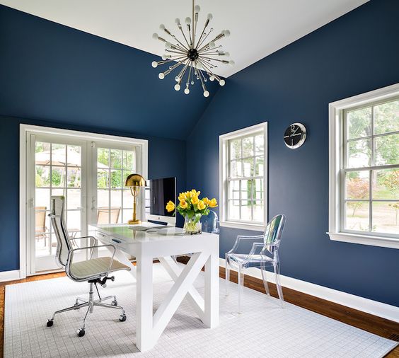 a clean home office with navy walls is given much negative space and light to avoid boring and dark looks