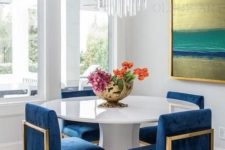 13 a white geometric table with a round tabletop makes the bright blue chairs stand out a lot