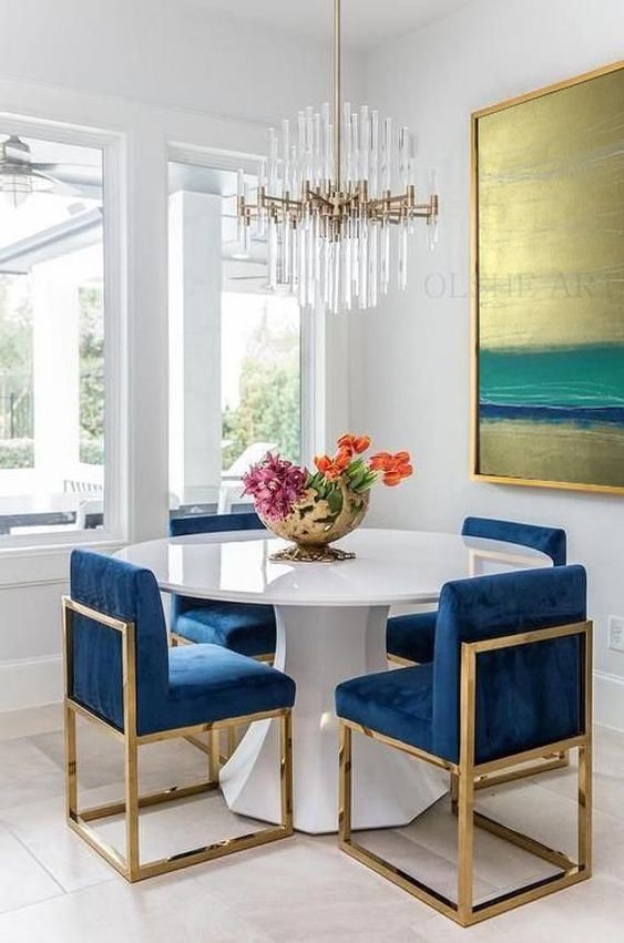 a white geometric table with a round tabletop makes the bright blue chairs stand out a lot