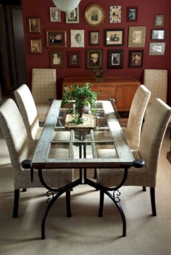 A vintage inspired dining table featuring a vintage door, forged legs and a glass tabletop