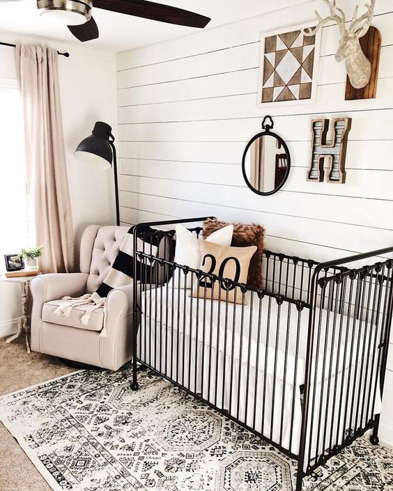 a farmhouse nursery with a woodland boho gallery wall, a printed rug and dramatic black touches