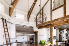 16 a white barndominium kitchen with wooden beams, pendant lamps, an oversized kitchen island