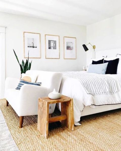 a stylish coastal bedroom finished off with a creamy loveseat on wooden legs for a cozier feel and comfortable sitting