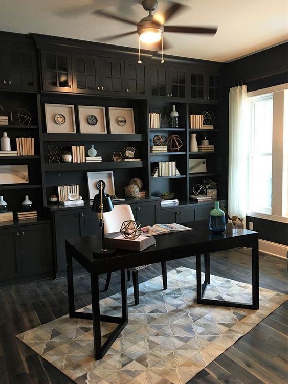 A black home office with a built in wall unit and a polished desk is refreshed with some neutral touches