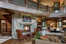 19 a cozy rustic barndominium space done with stone and wood, with warm-colored leather and a fireplace