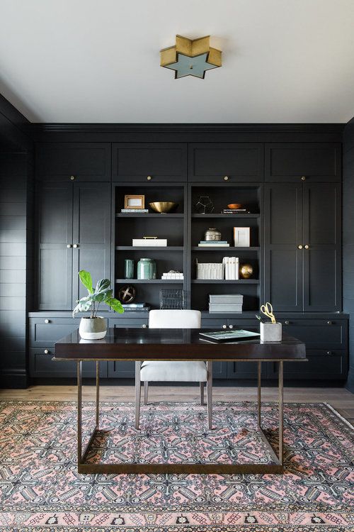 a retro-inspired home office in black with an oversized storage unit, a rich stained desk and a star lamp