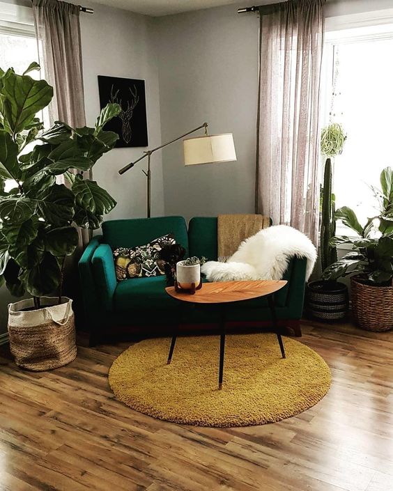an emerald loveseat and a mustard rug create a chic mid-century modern nook in bright tones