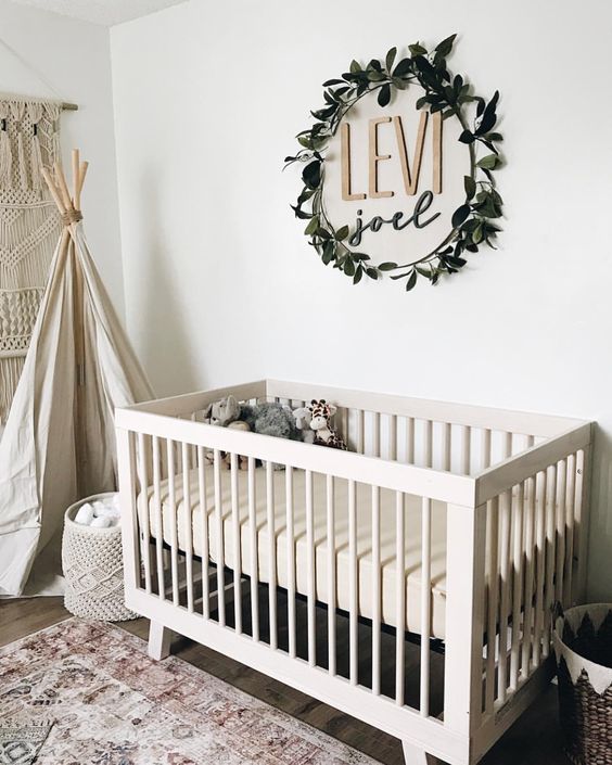 the name placed on the wall and accented with a fake greenery wreath is a stylish idea for a gender-neutral nursery