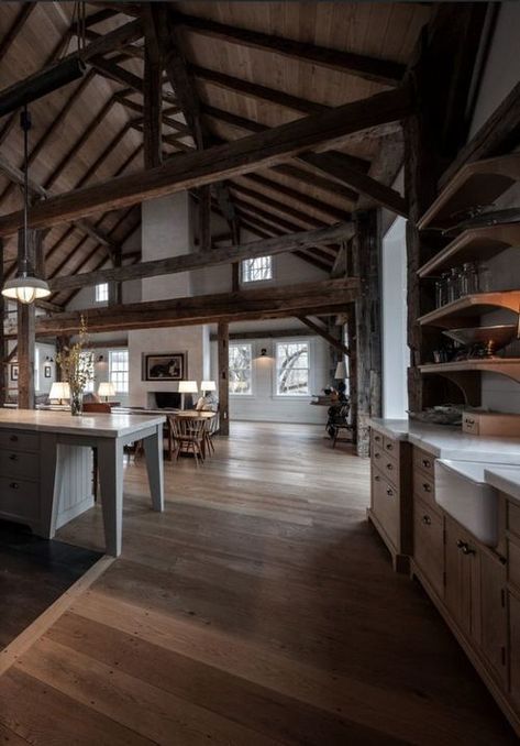 a cozy barndominium with multiple beams and much stained wood in decor, a white fireplace