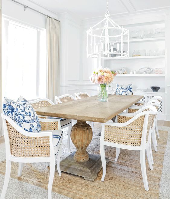 a rustic wooden table on large legs and cane chairs make up a traditional beach dining space