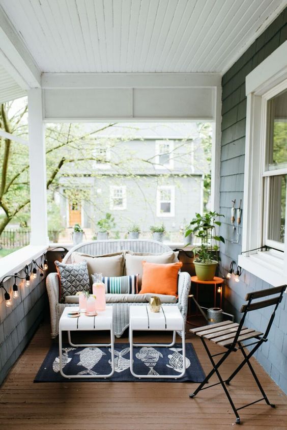 a white wicker loveseat can be easily squeezed into a small porch like this one to create a sitting space here