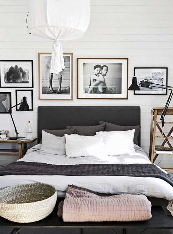 a Nordic black and white bedroom with a black bed, a gallery wall, mismatching wooden nightstands