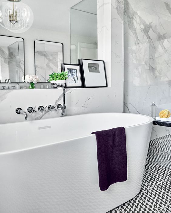 a contemporary Parisian bathroom with an oval tub, artworks, white marble tiles and a geometric floor