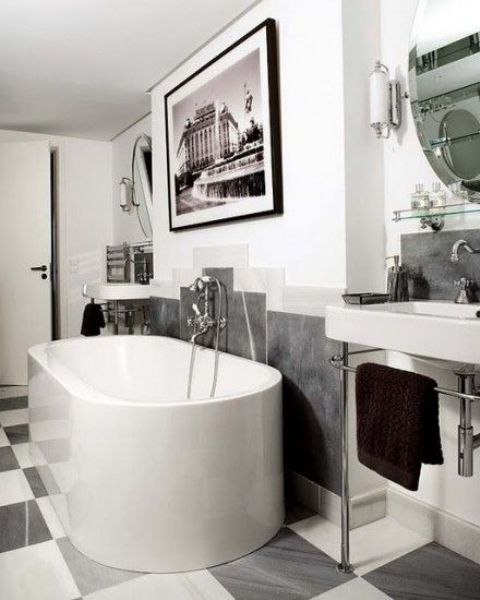 A contemporary monochromatic bathroom with a statement artwork, an oval tub, a free standing sink and a checked floor