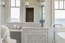 a contemporary tub, windows with sea views and a vintage meets contemporary vanity plus an acrylic chair
